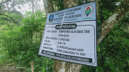 Papan Proyek Jalan Usaha Tani di Desa Balekambang Ditempelkan di Pohon