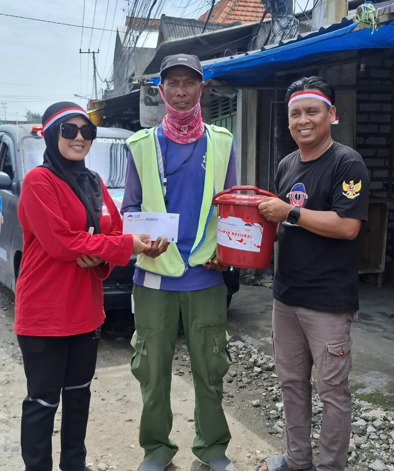 Foto : Ketua LSM Cakrawala Keadilan, Hilal Ahmar (kanan) bersama istri (kiri) memberikan bingkisan dan santunan kepada petugas penyebarang jalan (tengah). Foto: Defir